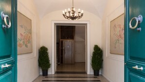 Un pasillo con puertas color turquesa, un candelabro y dos macetas.