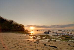 Una playa con barcos y un atardecer.