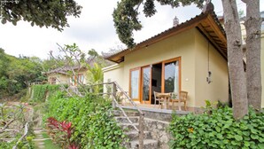 Una casa con una escalera de piedra que lleva a una terraza de madera con mobiliario exterior.