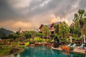 Ein Resort mit Schwimmbad, üppiger Vegetation und einem mehrstöckigen Gebäude.