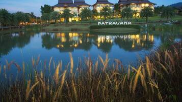 A hotel with a large body of water in front, palm trees, and a well-lit building with the name 'PATRAVANA' visible.