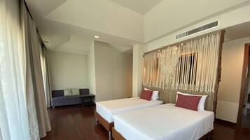 A hotel room with two beds, a sofa, and a large window with curtains.