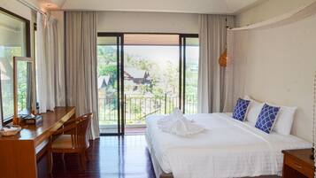 Habitación de hotel con una cama grande, un escritorio y una silla. Tiene un balcón con vistas al exterior.
