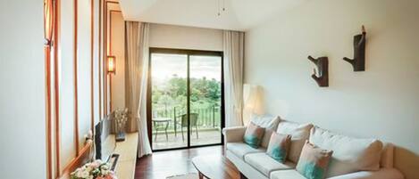 A modern living room with a sofa, a coffee table, a ceiling fan, and a view of the outdoors through a sliding door.
