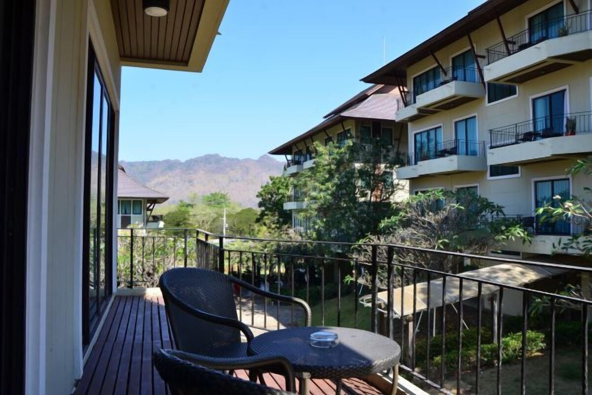 A balcony with a table and chairs, overlooking a mountainous landscape.