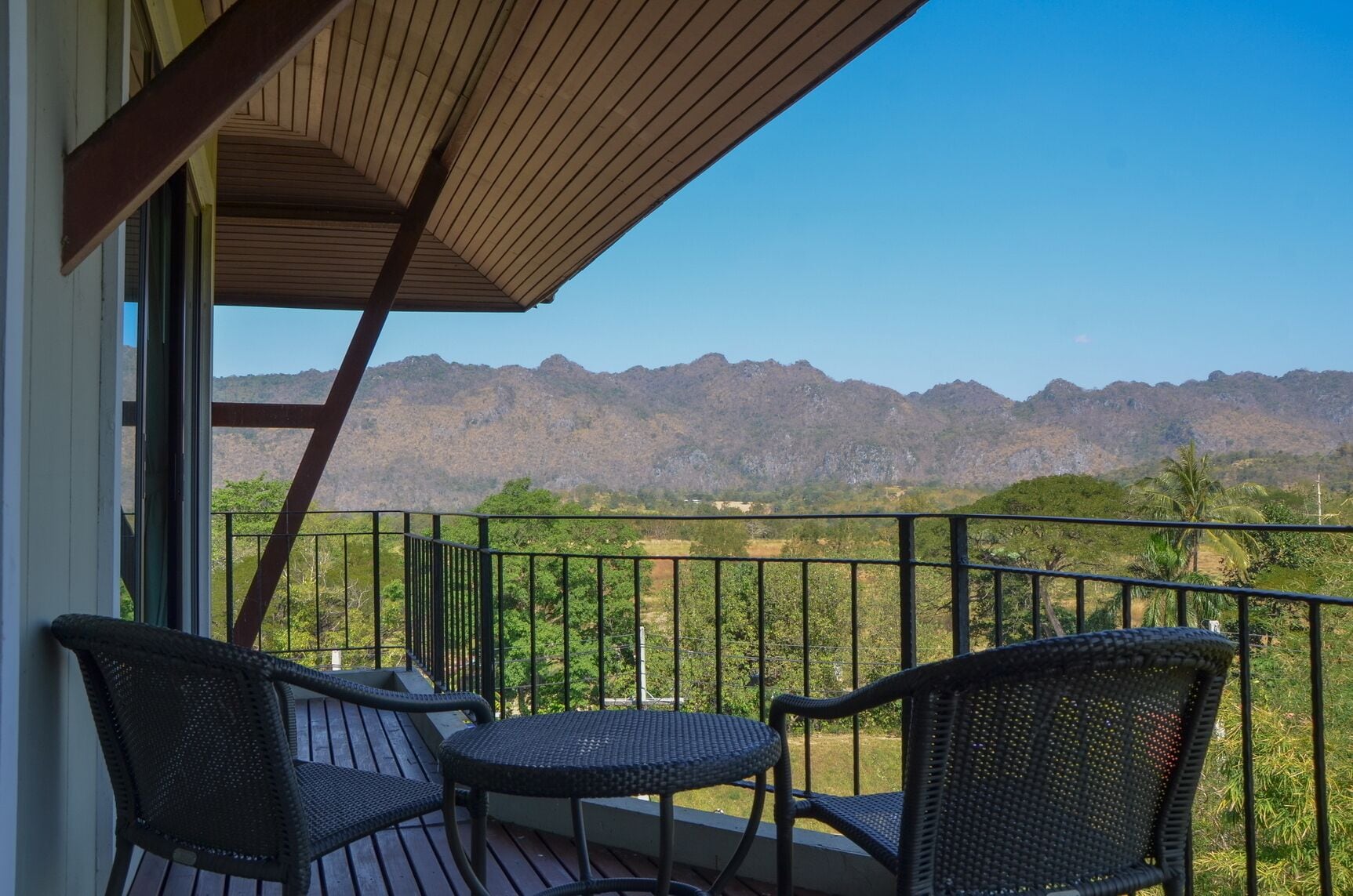 A balcony with wicker furniture and a view of mountains.