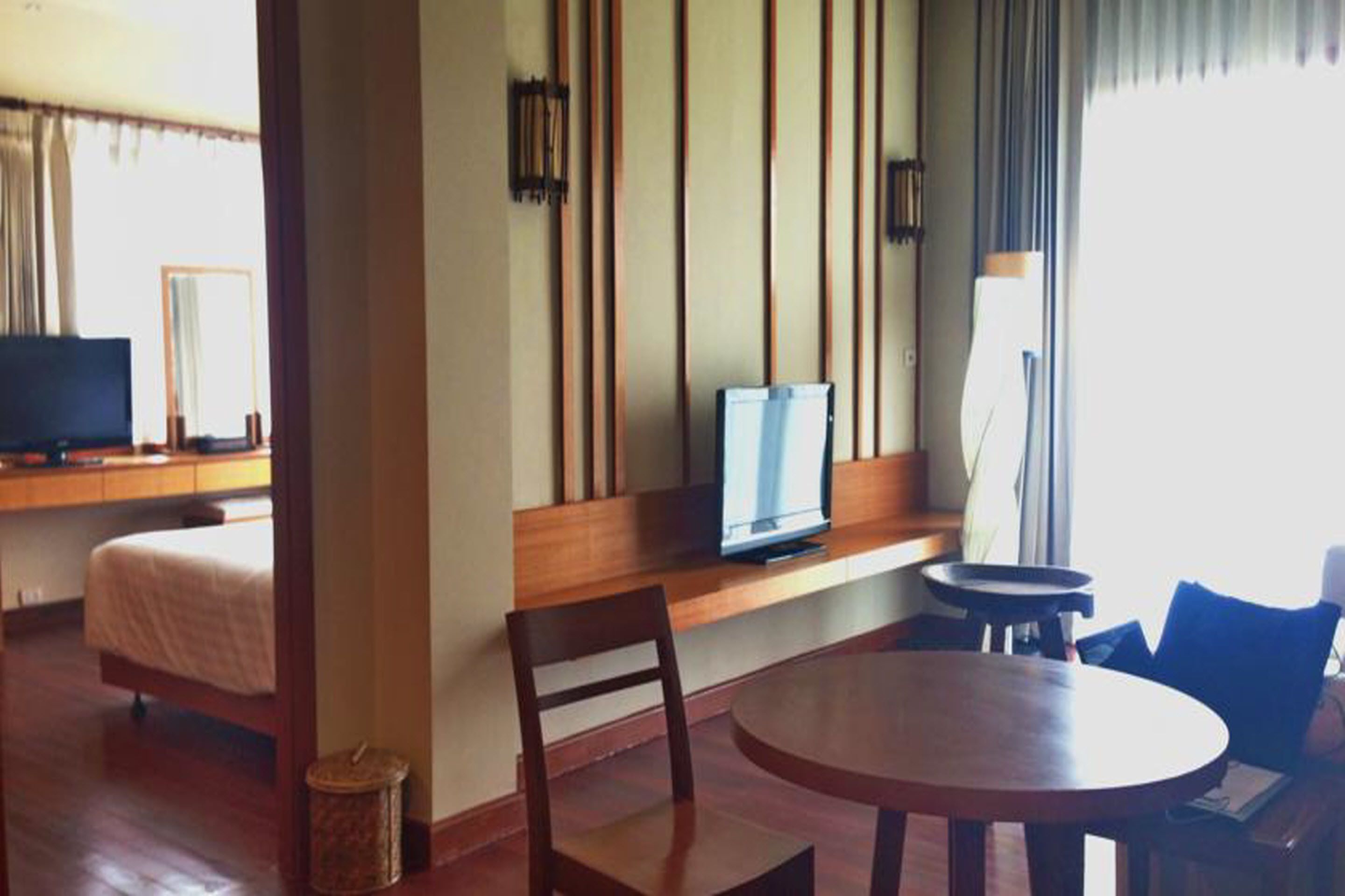 A hotel room with a bed, a TV, a wooden table, and a chair.