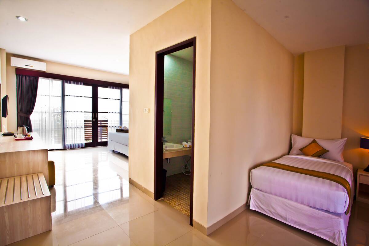 A hotel room with a bed, a desk, and a bathroom visible through an open door.