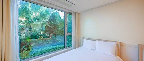 A hotel room with a large window, a bed, and a ceiling air conditioner.