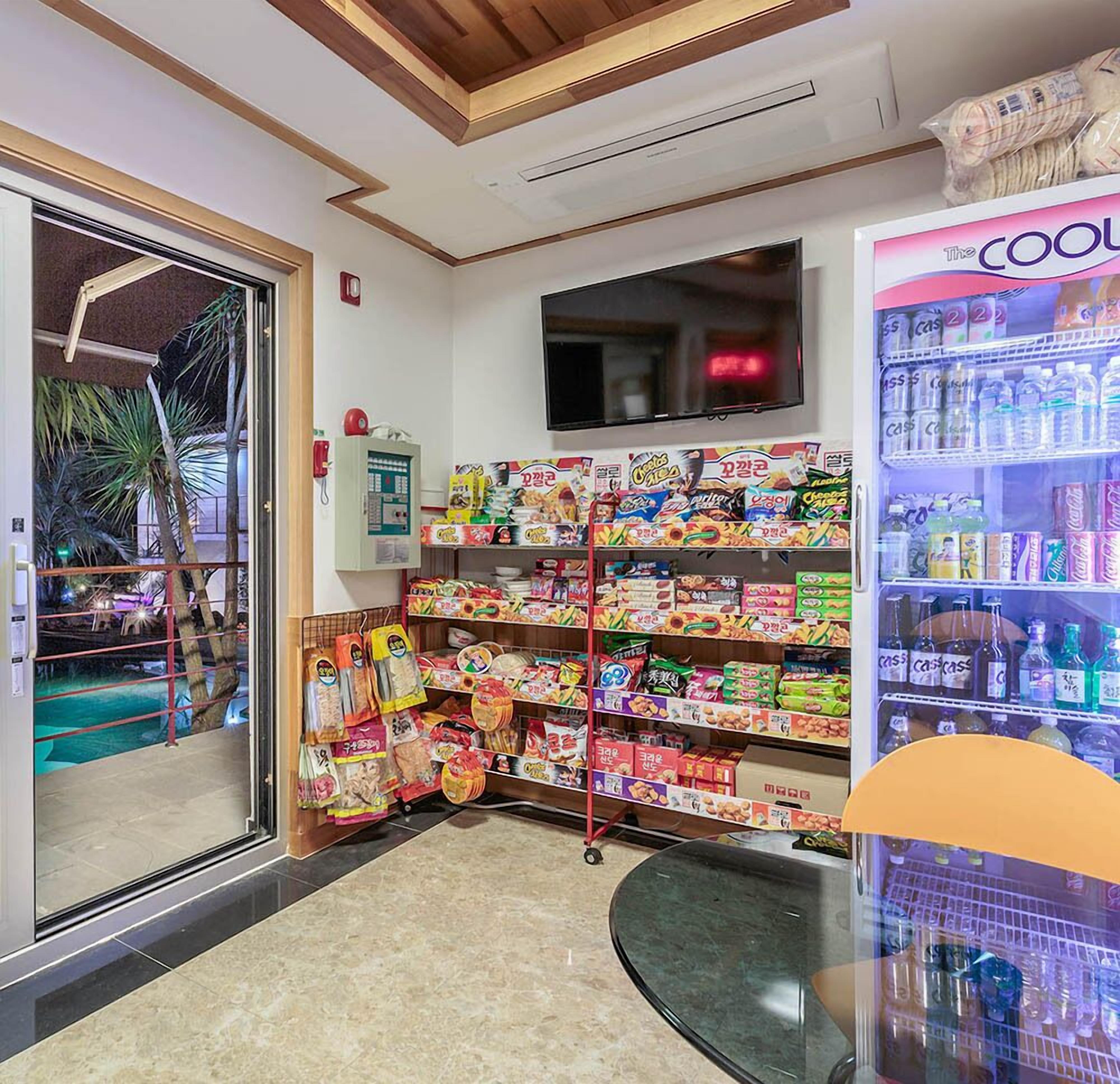 Un espace proposant des collations et des boissons, avec divers en-cas et boissons disponibles, un téléviseur fixé au mur et un petit espace extérieur visible à travers la porte en verre.