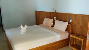 A single bed with a wooden headboard, two pillows, a bedside table, and a wall-mounted air conditioning unit. - Paradise Bungalows (Ko Pha-ngan)
