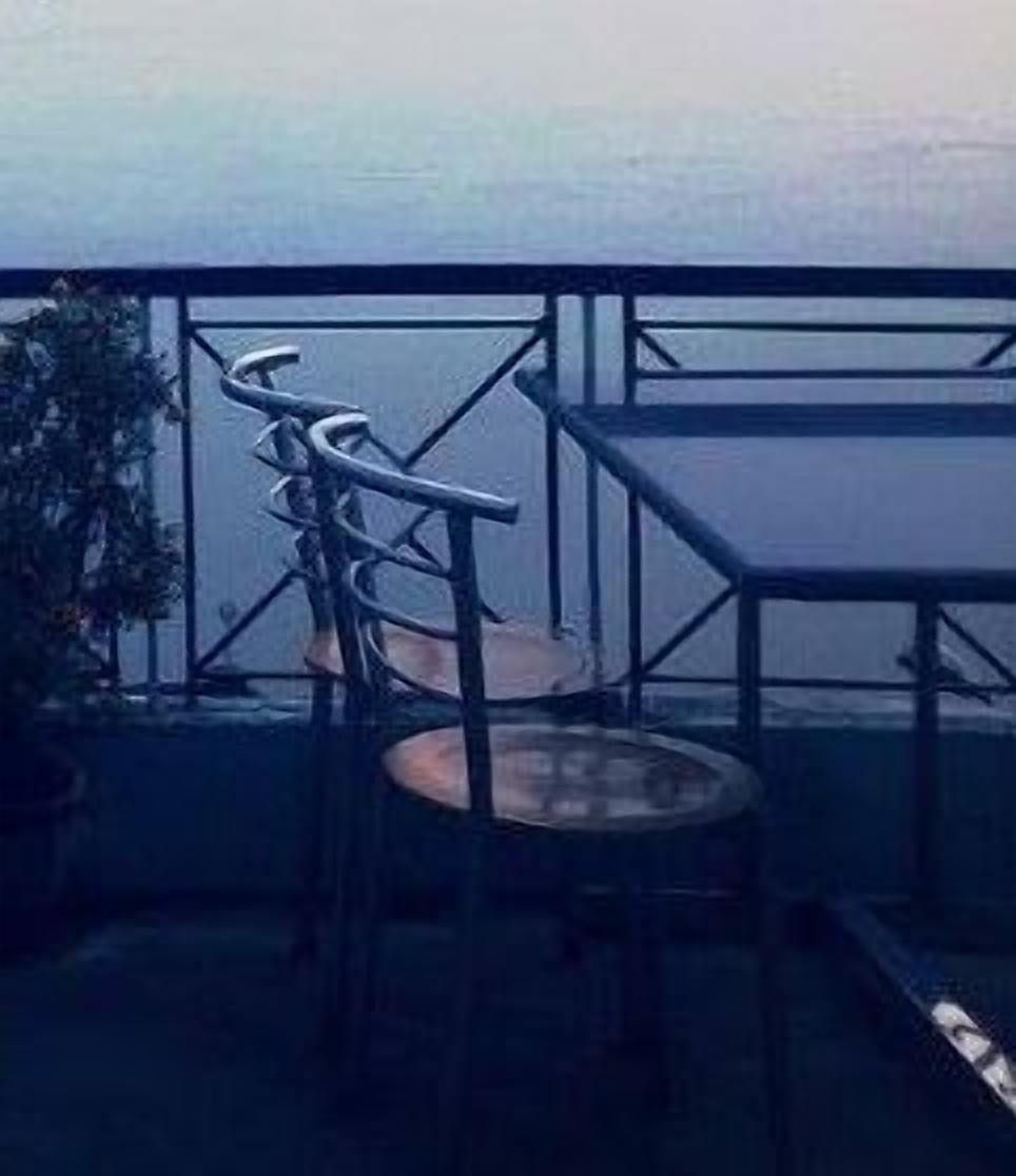 En balkon med gelænder, et rundt bord og en stol.
