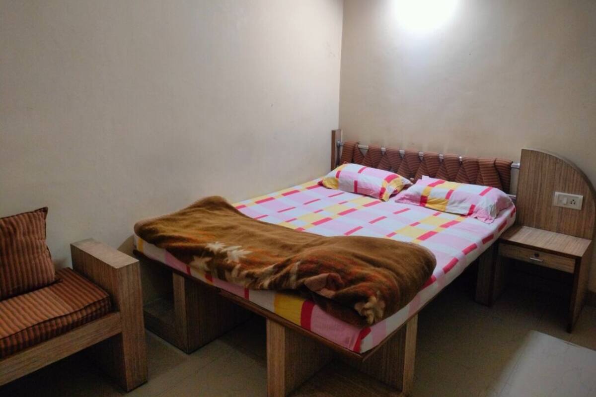 A small, neatly arranged bedroom with a bed, a chair, and a bedside table.