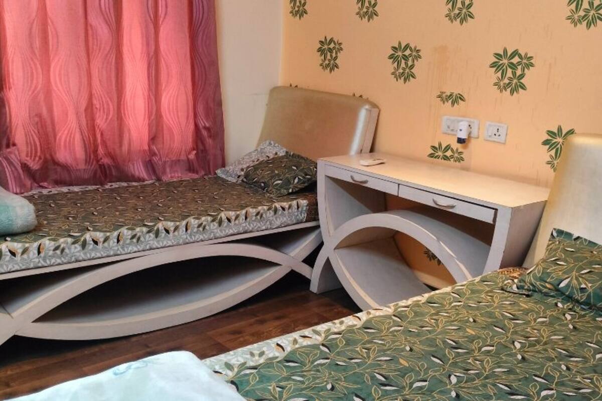 A room with two beds, a desk, and a chair.
