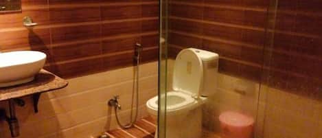 A bathroom with a glass-enclosed shower stall, a sink, and a toilet.