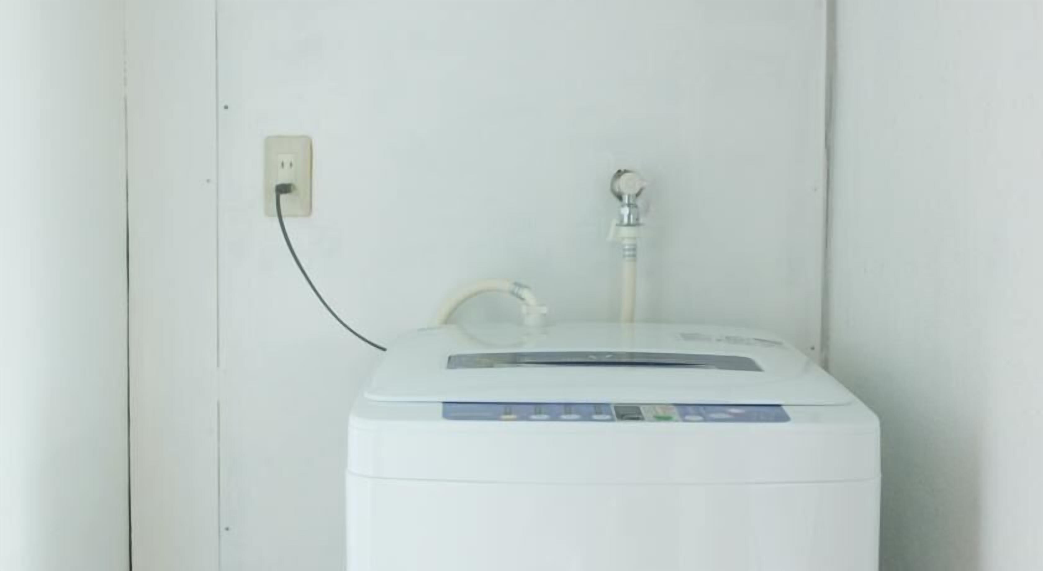 A white water heater with a control panel, a power outlet, and a water spout on a white wall.