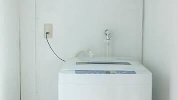 A white water heater with a control panel, a power outlet, and a water spout on a white wall.