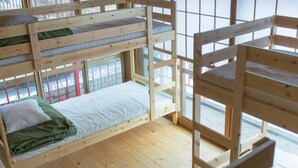A bunk bed room with a window, wooden flooring, and a green blanket on the lower bunk. - Nikkosan BackPackers Inn - Hostel (Nikko)