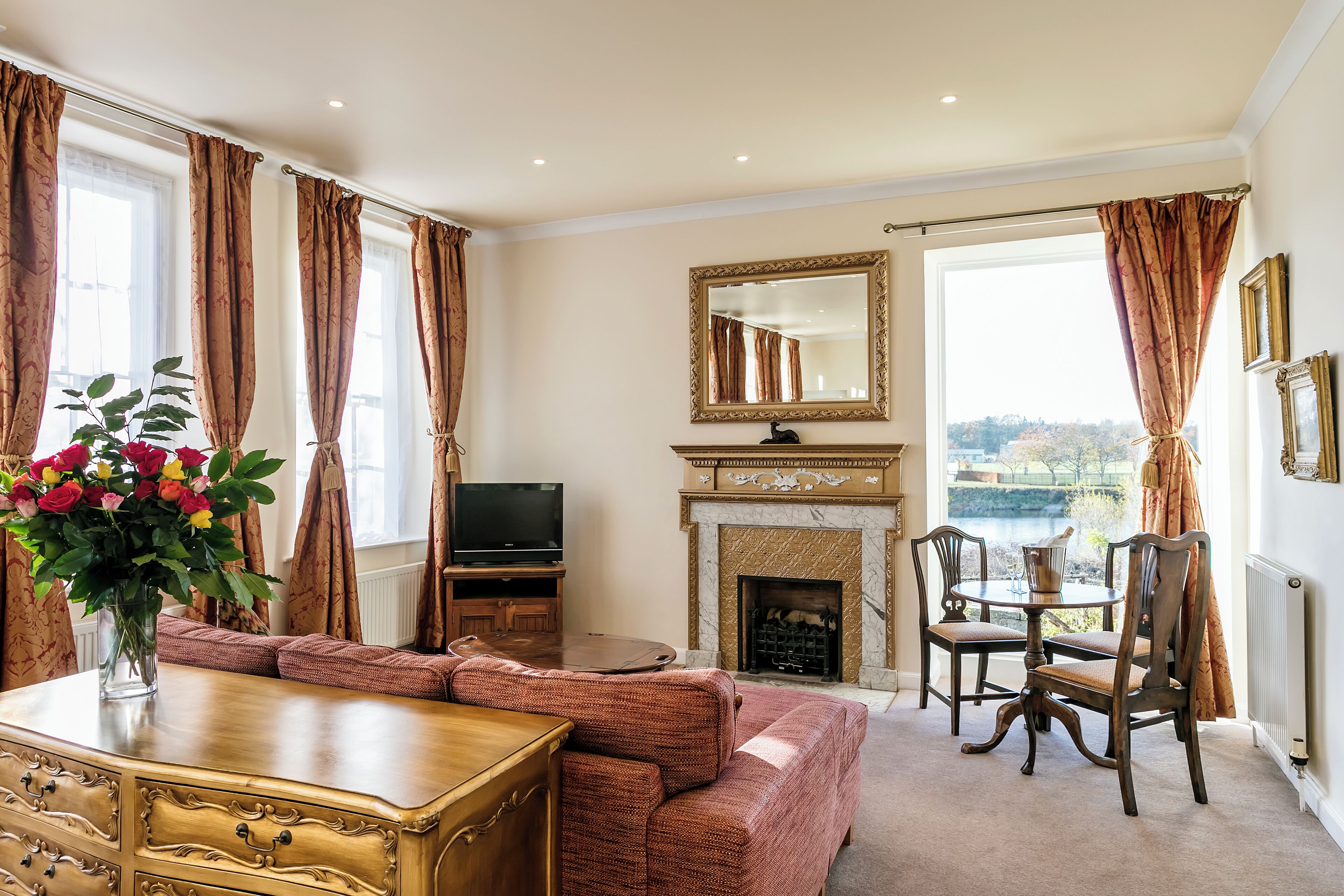 honeymoon suite, 1 king bed, river view, garden area | living area | flat-screen tv, books