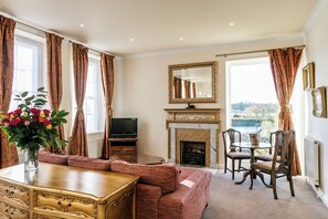 Suite – honeymoon, 1 kingsize-seng, elveutsikt, hageområde | Oppholdsområde | Flatskjerm-TV og bøker