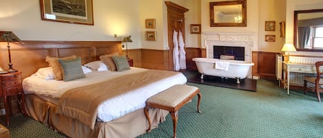 Un dormitorio espacioso con una cama grande, un banco, una chimenea, una bañera y un cabecero de madera.