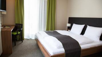 Een hotelkamer met een bed, een bureau, een stoel en een televisie.