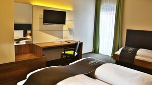 A hotel room with two beds, a desk, a TV, and a window with curtains. - RiKu HOTEL Weissenhorn (Weissenhorn)