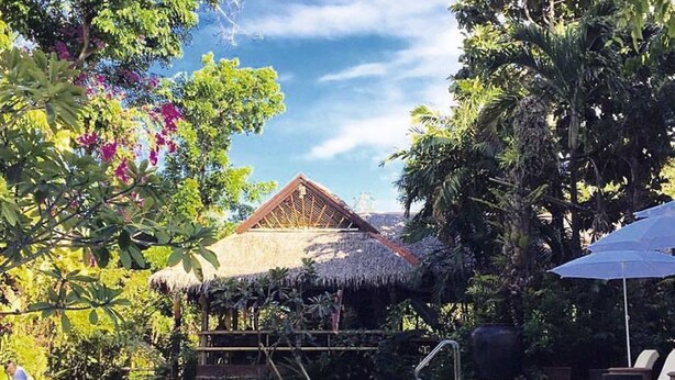 A swimming pool with a thatched-roof structure in the background, surrounded by lush greenery. - The Sun Villa Resort and Spa Hilltop (Boracay Island)