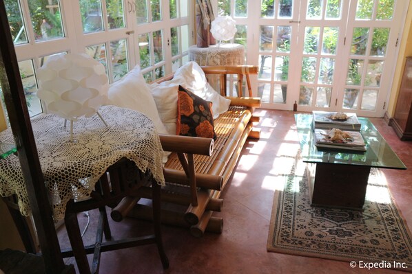 A cozy room with a wooden bench, a glass table, and a lace-covered chair.