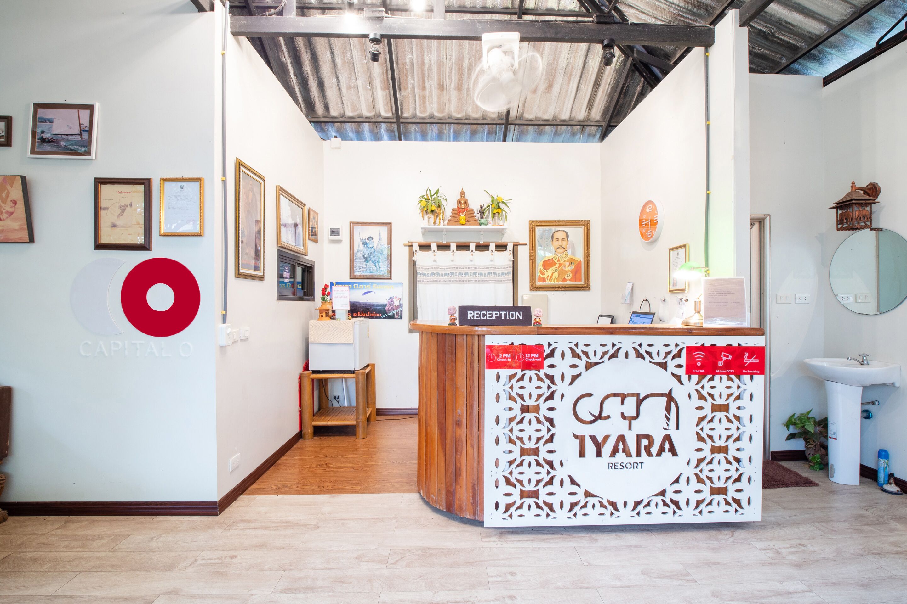 A reception desk with a sign reading "TYARA RESORT" and a "RECEPTION" sign above it. There are framed pictures on the wall and a large red logo on the left.