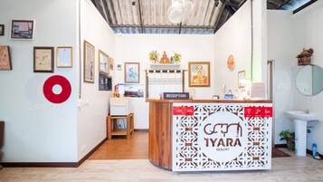A reception desk with a sign reading "TYARA RESORT" and a "RECEPTION" sign above it. There are framed pictures on the wall and a large red logo on the left.