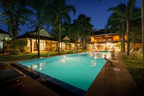A swimming pool with lounge chairs and a building with a balcony in the background. - CAPITAL O 834 Iyara Resort & Spa (Ko Chang)