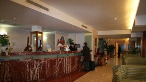 A hotel reception area with a marble counter, a clock, and a reception desk.