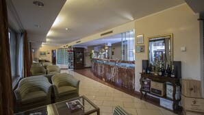 A hotel lobby with a reception desk, seating area, and a display of wine bottles.