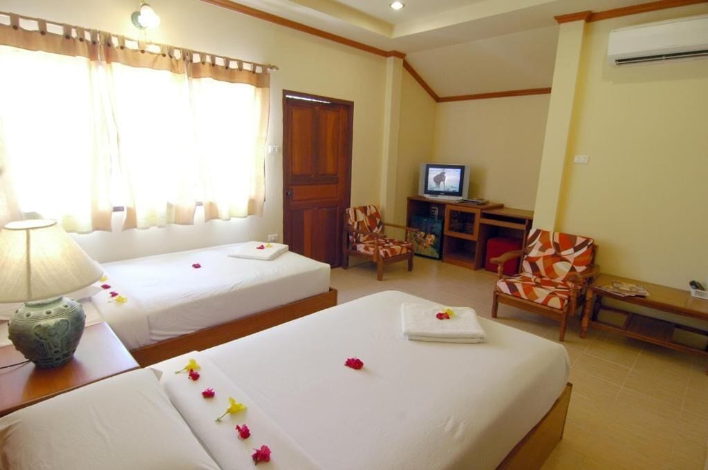 A hotel room with two beds, a television, a desk, and a chair.