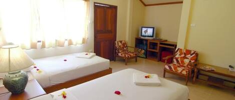 A hotel room with two beds, a television, a desk, and a chair.