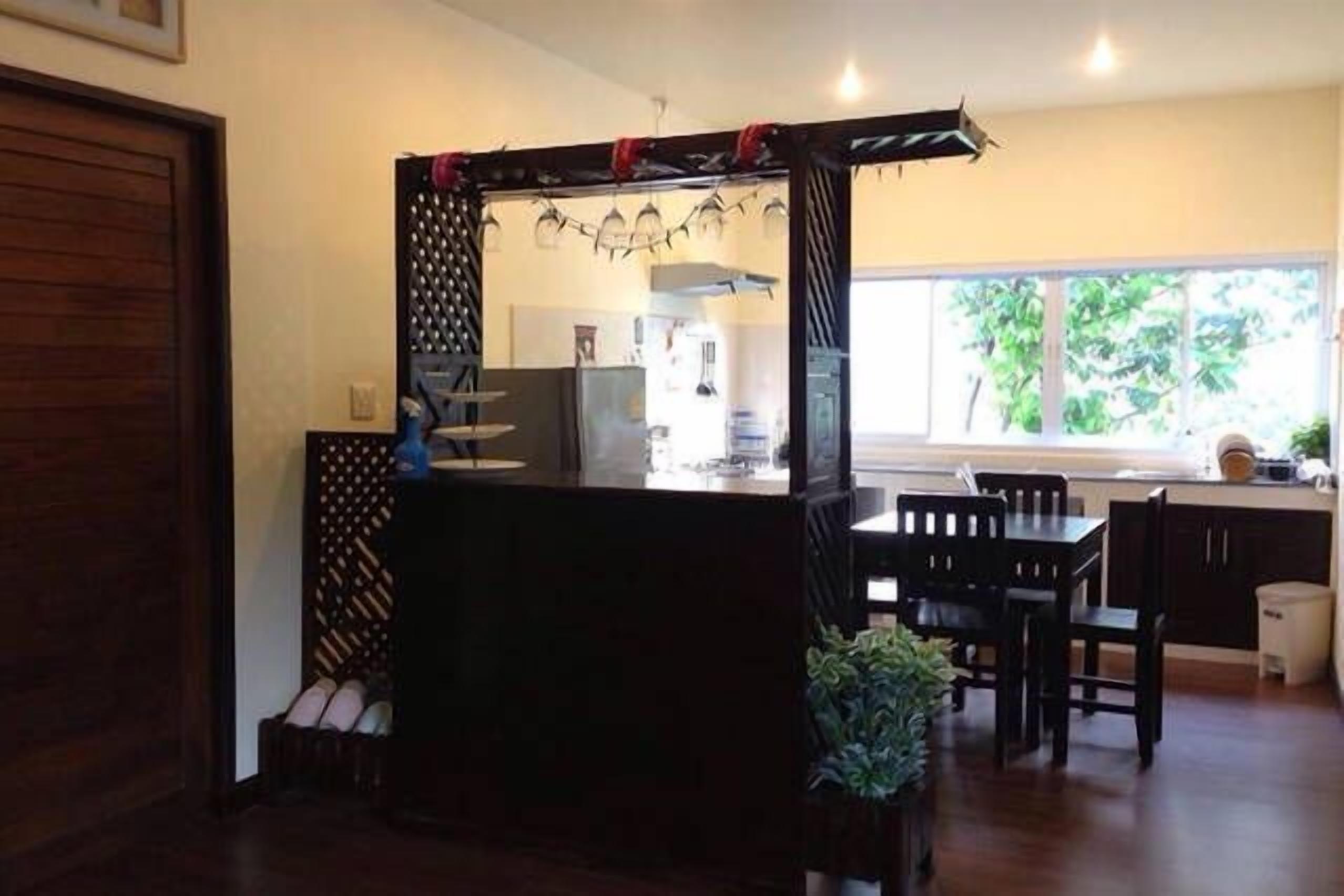 A compact kitchen with a central island, dark wooden cabinets, a dining area with chairs, and a window providing natural light.