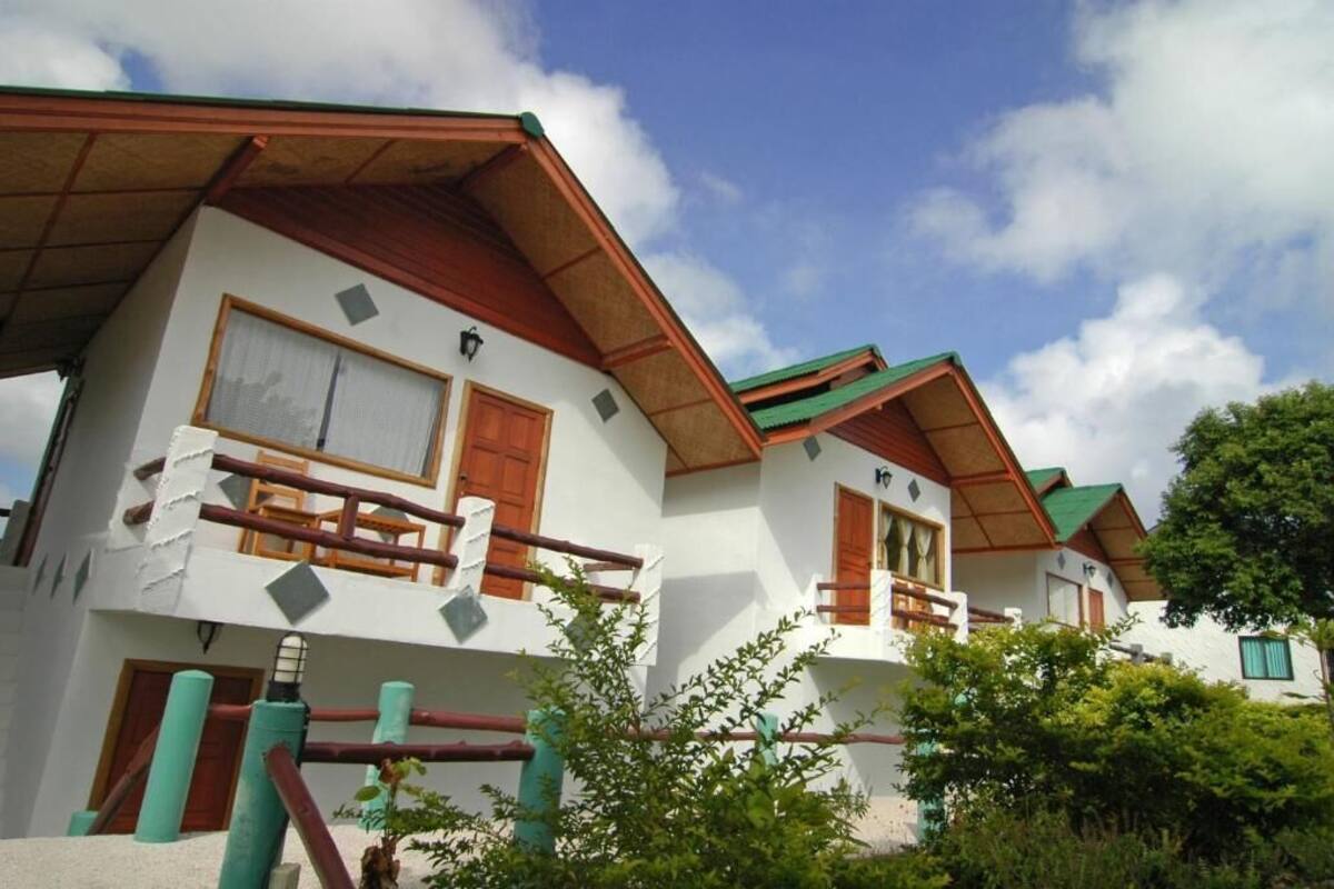 Una hilera de edificios blancos con balcones de madera y techos verdes.