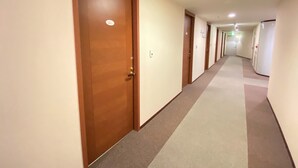 A hotel hallway with multiple doors, carpeted floors, and recessed ceiling lights. - Hotel 1-2-3 Kokura (Kitakyushu)