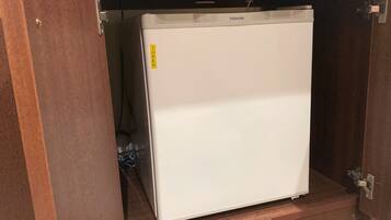 A white refrigerator under a wooden cabinet with a label that reads "TOP OPEN".