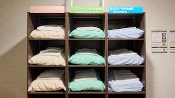 Estantes con opciones de ropa de cama etiquetadas en una habitación de hotel.