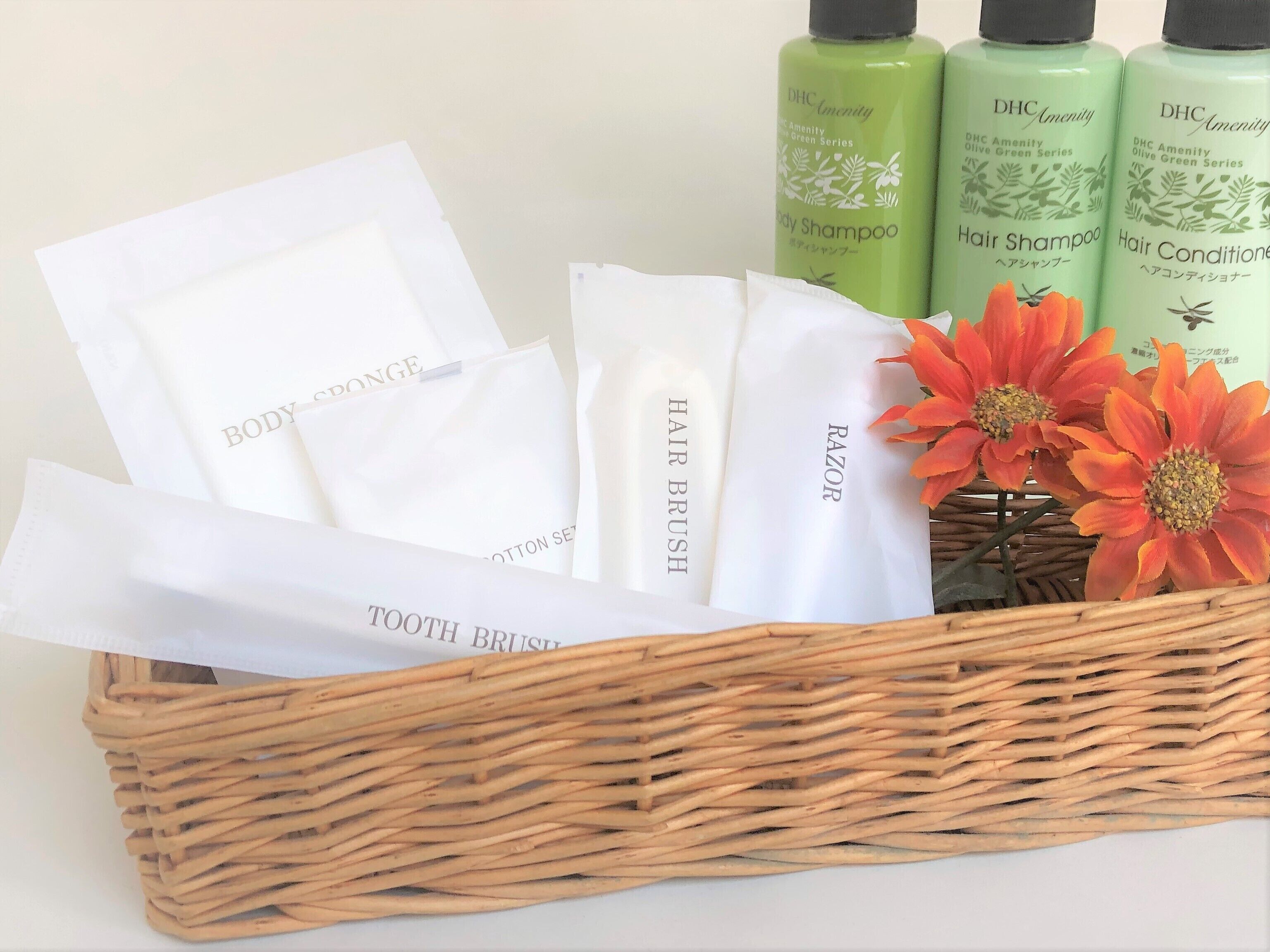 A wicker basket containing various personal care items including body sponge, hair brush, razor, and hair shampoo.