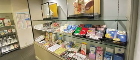 A bookstore with shelves of books and magazines, a display of postcards, and a framed artwork above the counter.