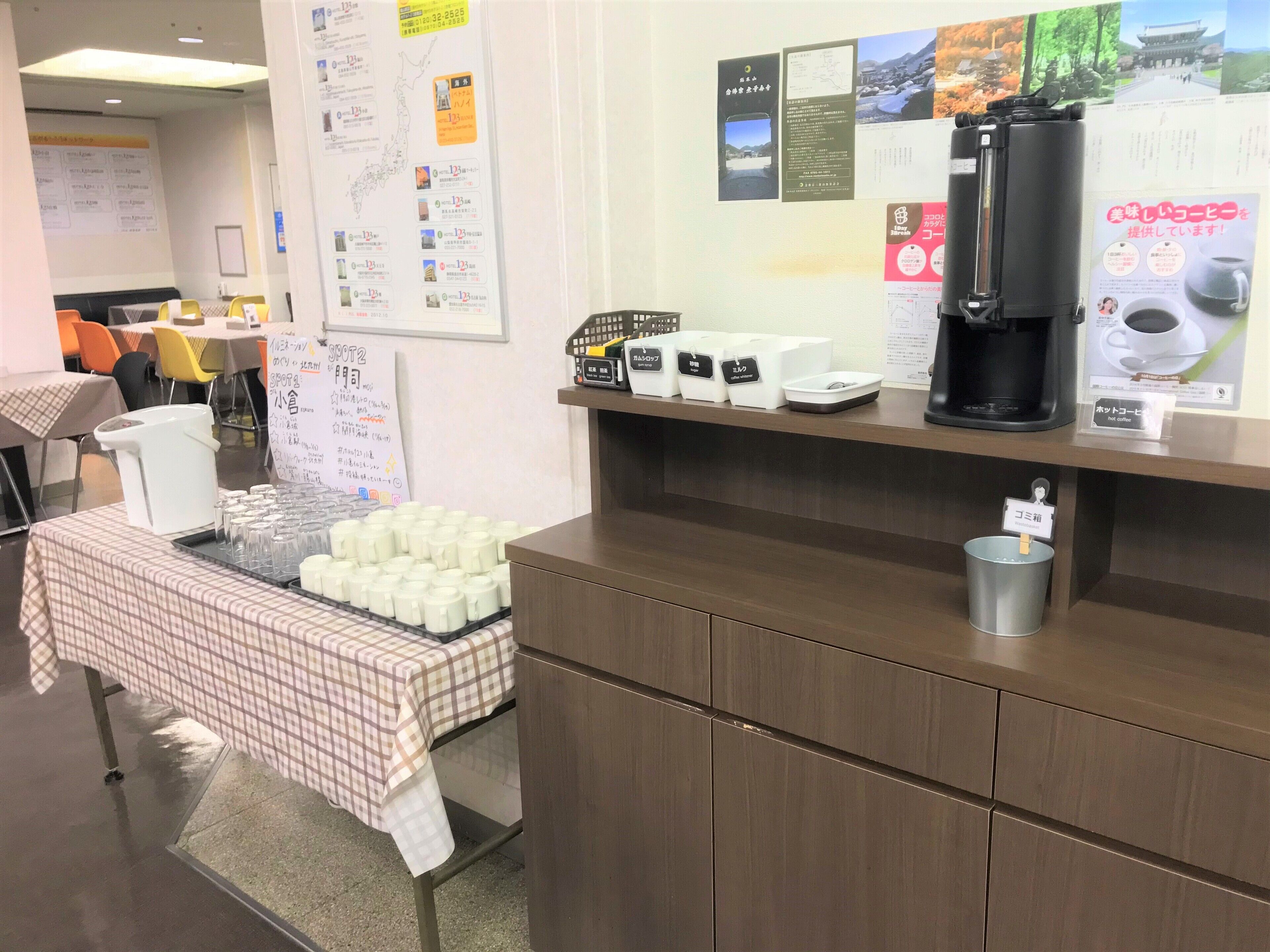 A coffee station with a coffee machine, cups, and a sign indicating hot coffee.