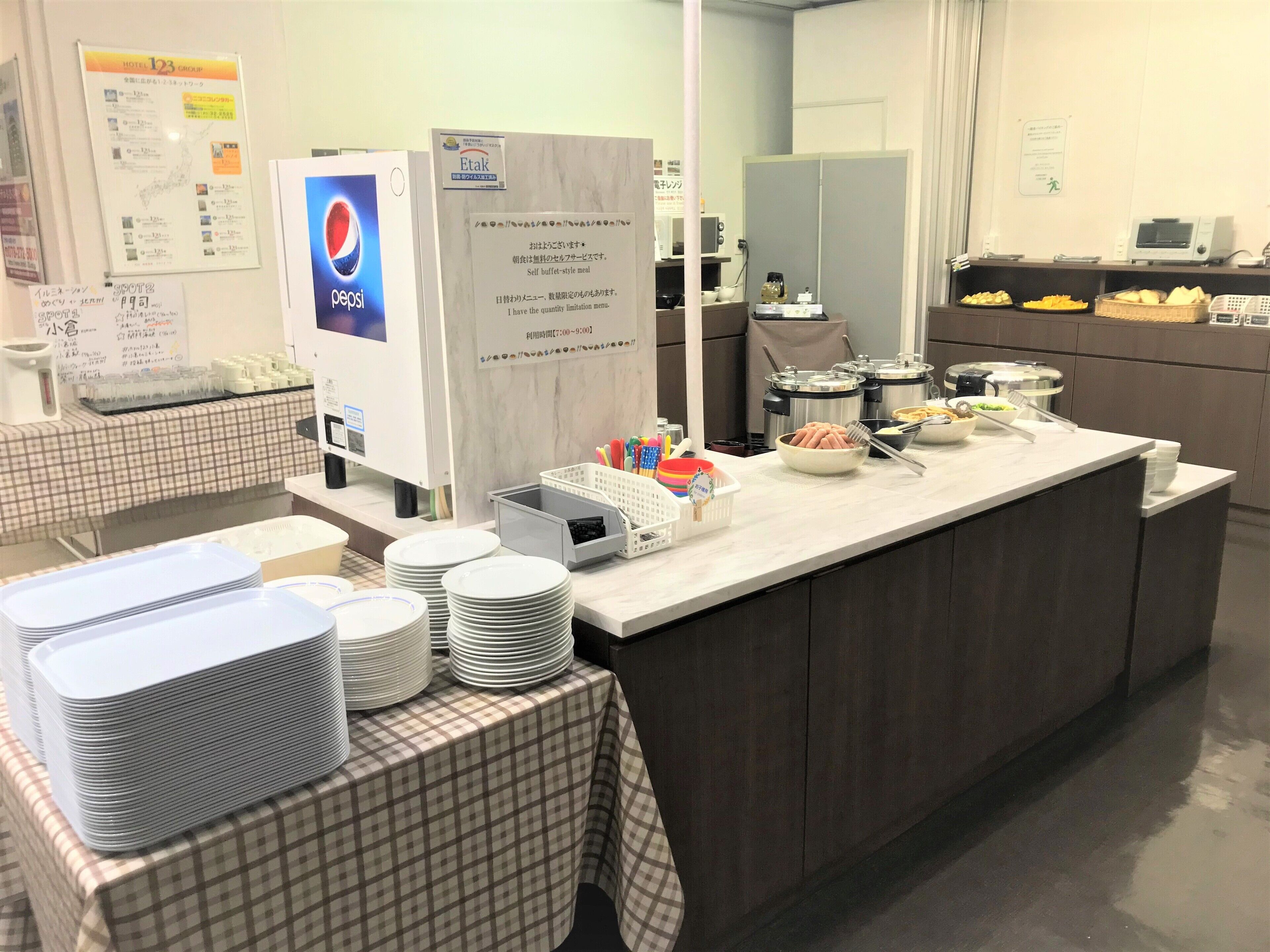 A buffet area with a Pepsi refrigerator, a self-service buffet-style meal sign, and various food items and utensils on the counter.