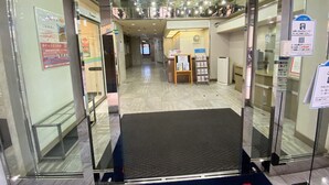 A hotel entrance with a reception desk, a digital display, and informational posters. - Hotel 1-2-3 Kokura (Kitakyushu)