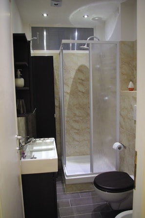 A bathroom with a shower enclosure, a toilet, and a sink. - In Roma Life (Rome)