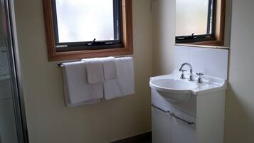 A bathroom with a white sink, a mirror above it, and a window with a wooden frame.