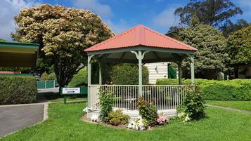 A gazebo with a red roof, surrounded by well-maintained grass and flowers, and a sign indicating a reception area.