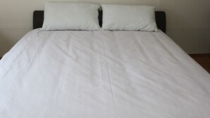 A bed with a white bedspread and two pillows. - Dongdaemun Guest House (Seoul)